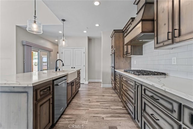 21813 Valley Vista Dr, Tehachapi, CA 93561 - kitchen featuring stainless steel appliances, custom range hood, light wood-type flooring, tasteful backsplash, and a center island with sink