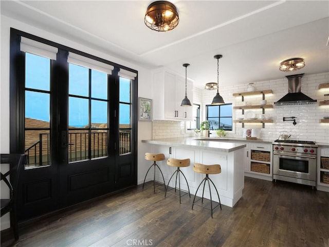 229 Marine Pl, Manhattan Beach, CA 90266 - kitchen with premium stove, wall chimney exhaust hood, tasteful backsplash, white cabinetry, and a kitchen bar