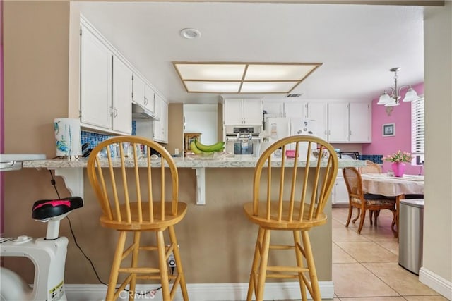 22024 Jeffers Ln, Saugus, CA 91350 - kitchen with a peninsula, freestanding refrigerator, white cabinetry, and light tile patterned floors