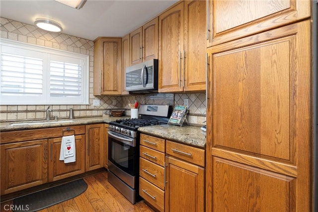 14913 San Ardo Dr, La Mirada, CA 90638 - kitchen featuring appliances with stainless steel finishes, light wood-type flooring, tasteful backsplash, and brown cabinets