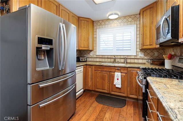 14913 San Ardo Dr, La Mirada, CA 90638 - kitchen with stainless steel appliances, tasteful backsplash, wood finished floors, brown cabinets, and light stone countertops