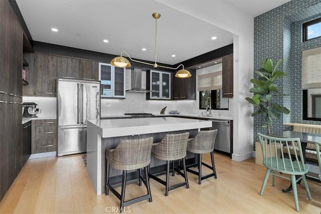 802 Bard St, Hermosa Beach, CA 90254 - kitchen featuring stainless steel appliances, wall chimney range hood, light countertops, dark brown cabinets, and light wood-type flooring