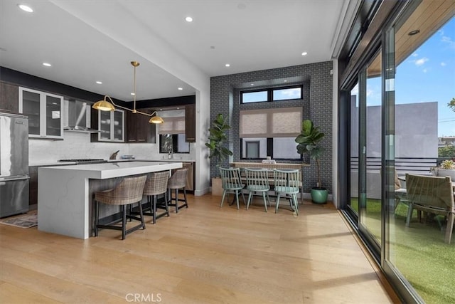 802 Bard St, Hermosa Beach, CA 90254 - kitchen featuring wall chimney exhaust hood, appliances with stainless steel finishes, a center island, light countertops, and light wood finished floors