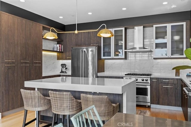 802 Bard St, Hermosa Beach, CA 90254 - kitchen featuring high end appliances, wall chimney exhaust hood, a center island, a breakfast bar area, and decorative backsplash