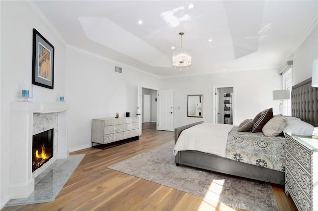 29614 Ridgeway Dr, Agoura Hills, CA 91301 - bedroom featuring a chandelier, a tray ceiling, wood finished floors, a tile fireplace, and ornamental molding