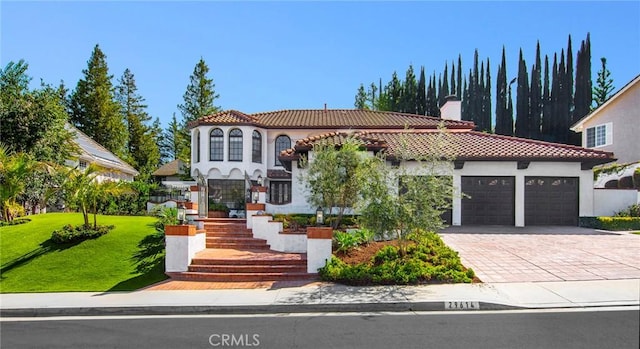 29614 Ridgeway Dr, Agoura Hills, CA 91301 - mediterranean / spanish-style house featuring a garage, decorative driveway, a tile roof, a front lawn, and a chimney