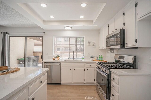 21715 Laurelrim Dr Unit D, Diamond Bar, CA 91765 - kitchen featuring appliances with stainless steel finishes, a tray ceiling, light wood-type flooring, recessed lighting, and white cabinets