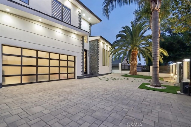 10418 Rubio Ave, Granada Hills, CA 91344 - view of front facade featuring decorative driveway, stone siding, stucco siding, and an attached garage