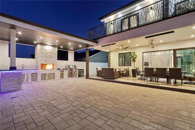 10418 Rubio Ave, Granada Hills, CA 91344 - patio at night with a balcony, exterior kitchen, ceiling fan, outdoor dining space, and a patio