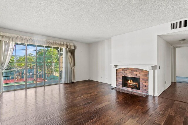 3611 S Bear St Unit K, Santa Ana, CA 92704 - unfurnished living room featuring wood finished floors, a textured ceiling, and a brick fireplace