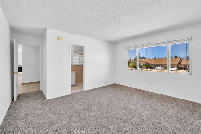 7535 Hilton Ave, Yucca Valley, CA 92284 - unfurnished bedroom featuring carpet floors, a textured ceiling, and ensuite bathroom