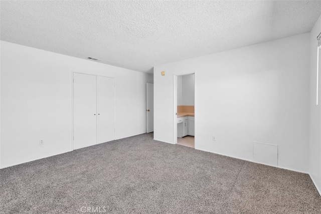 7535 Hilton Ave, Yucca Valley, CA 92284 - unfurnished bedroom featuring carpet floors, a textured ceiling, a closet, and connected bathroom