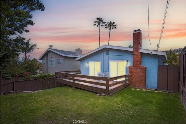34561 Calle Portola, Dana Point, CA 92624 - back of property at dusk featuring a deck, a fenced backyard, stucco siding, and a chimney