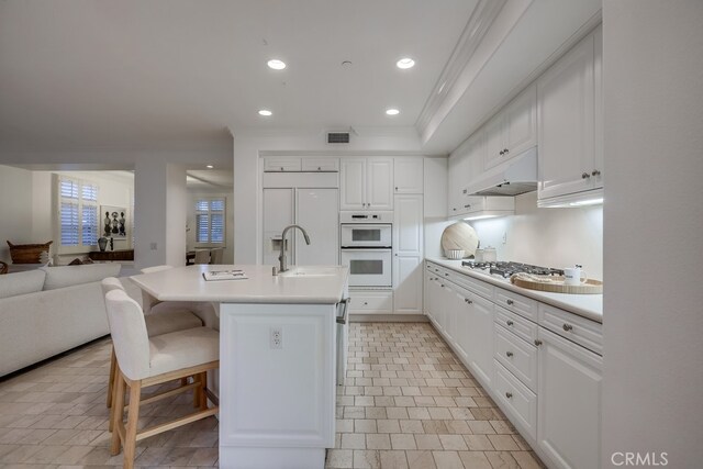 2569 Bungalow Pl, Corona Del Mar, CA 92625 - kitchen featuring open floor plan, white cabinets, crown molding, gas stovetop, and under cabinet range hood