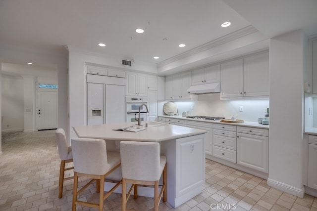2569 Bungalow Pl, Corona Del Mar, CA 92625 - kitchen with under cabinet range hood, crown molding, light countertops, oven, and white cabinetry