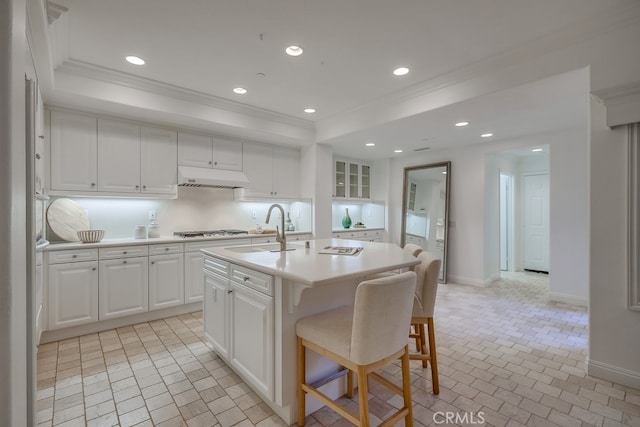 2569 Bungalow Pl, Corona Del Mar, CA 92625 - kitchen with ornamental molding, under cabinet range hood, stainless steel gas cooktop, light countertops, and white cabinets