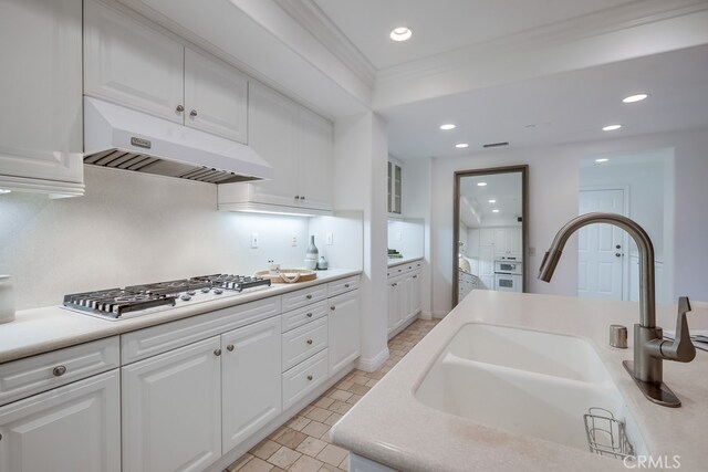 2569 Bungalow Pl, Corona Del Mar, CA 92625 - kitchen with under cabinet range hood, stainless steel gas cooktop, white cabinets, recessed lighting, and light countertops