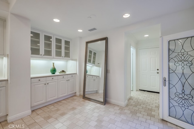 2569 Bungalow Pl, Corona Del Mar, CA 92625 - kitchen featuring white cabinets, glass insert cabinets, recessed lighting, light countertops, and brick patterned floors