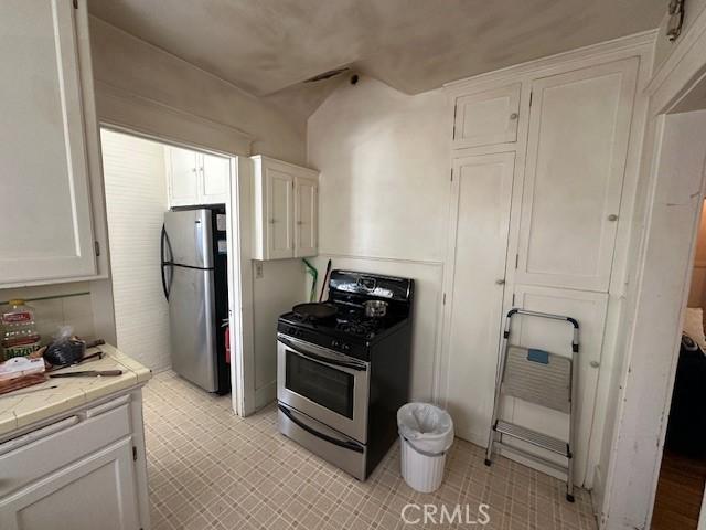 1045 Gladys Ave, Long Beach, CA 90804 - kitchen featuring stainless steel appliances, tile countertops, white cabinetry, and light flooring