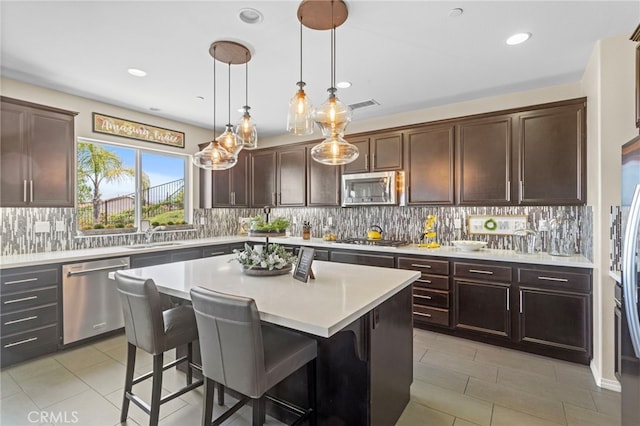 44316 Revana St, Temecula, CA 92592 - kitchen with appliances with stainless steel finishes, light countertops, a kitchen breakfast bar, a center island, and backsplash