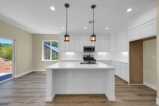 5350 Filbert St, Paradise, CA 95969 - kitchen with stainless steel microwave, healthy amount of natural light, a center island with sink, light countertops, and recessed lighting