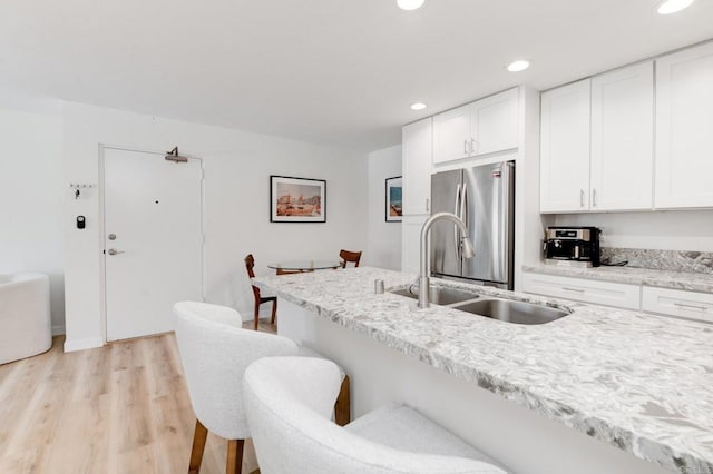 4600 Lamont St Unit 106, San Diego, CA 92109 - kitchen with freestanding refrigerator, a breakfast bar area, light wood-style floors, white cabinets, and recessed lighting