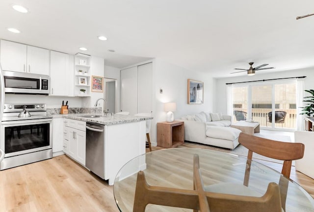 4600 Lamont St Unit 106, San Diego, CA 92109 - kitchen with appliances with stainless steel finishes, open shelves, a peninsula, light wood-style flooring, and recessed lighting