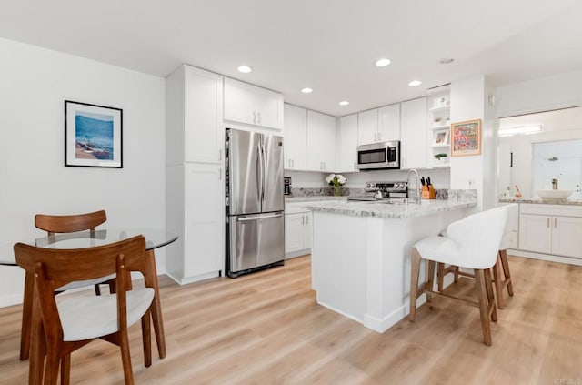 4600 Lamont St Unit 106, San Diego, CA 92109 - kitchen featuring appliances with stainless steel finishes, open shelves, white cabinets, a peninsula, and recessed lighting