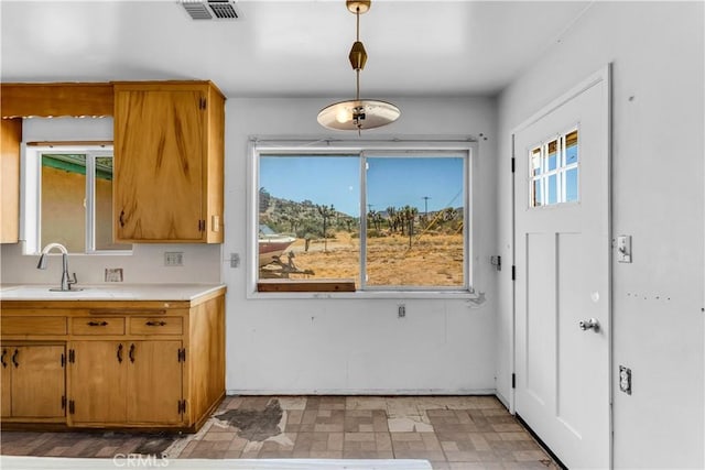 57136 Navajo Trl, Yucca Valley, CA 92284 - kitchen featuring light countertops, hanging light fixtures, and brown cabinets