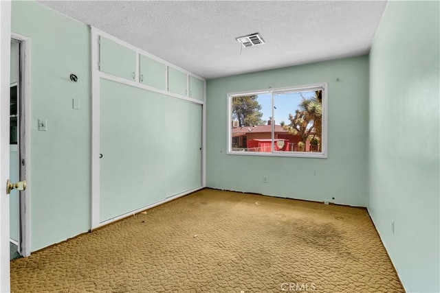 57136 Navajo Trl, Yucca Valley, CA 92284 - unfurnished bedroom featuring carpet flooring, a textured ceiling, and a closet