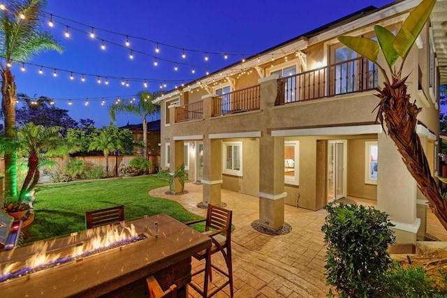 13748 Torrey Glenn Rd, San Diego, CA 92129 - back of house at night featuring a balcony, stucco siding, an outdoor fire pit, and a patio area