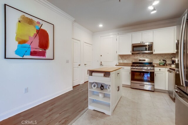 6938 Laurel Canyon Blvd Unit 101, North Hollywood, CA 91605 - kitchen featuring appliances with stainless steel finishes, ornamental molding, butcher block counters, white cabinetry, and open shelves