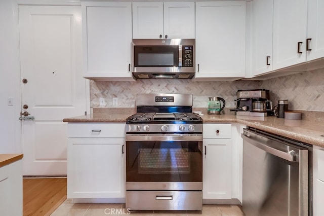 6938 Laurel Canyon Blvd Unit 101, North Hollywood, CA 91605 - kitchen featuring appliances with stainless steel finishes, white cabinets, tasteful backsplash, light wood finished floors, and light stone counters