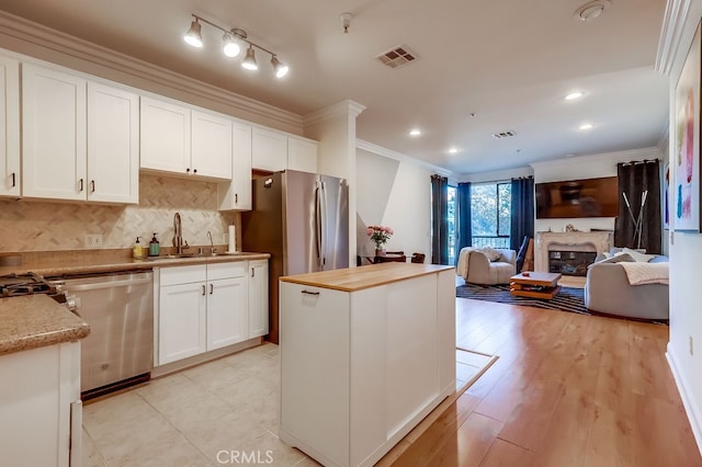 6938 Laurel Canyon Blvd Unit 101, North Hollywood, CA 91605 - kitchen with appliances with stainless steel finishes, crown molding, open floor plan, white cabinetry, and a kitchen island