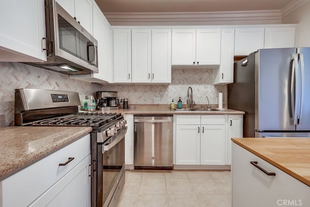 6938 Laurel Canyon Blvd Unit 101, North Hollywood, CA 91605 - kitchen with appliances with stainless steel finishes, white cabinetry, decorative backsplash, crown molding, and light tile patterned floors