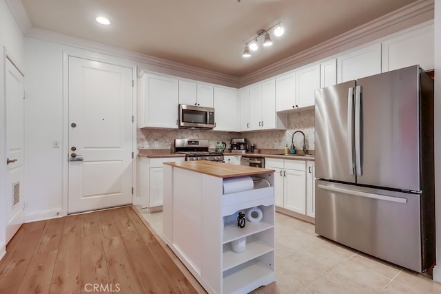 6938 Laurel Canyon Blvd Unit 101, North Hollywood, CA 91605 - kitchen featuring stainless steel appliances, butcher block counters, open shelves, white cabinetry, and ornamental molding