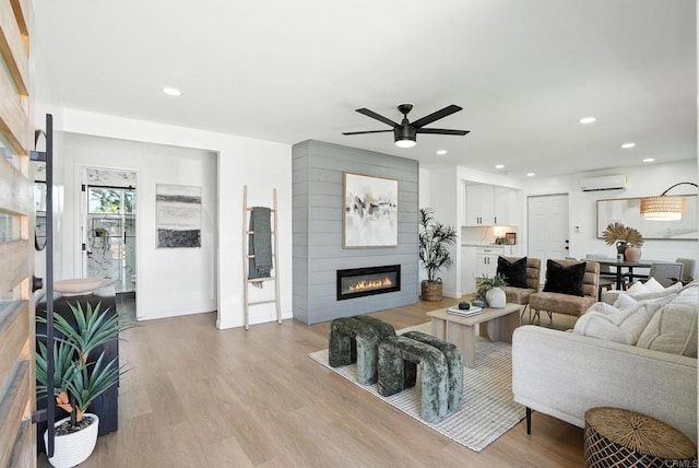 4862 Kesling Ct, San Diego, CA 92117 - living room with a large fireplace, a wall mounted AC, ceiling fan, light wood-style floors, and recessed lighting