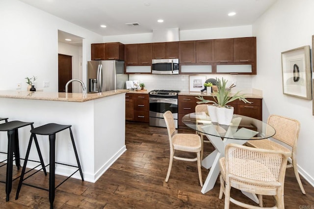 10667 Golden Willow Unit 152, San Diego, CA 92130 - kitchen featuring stainless steel appliances, a kitchen breakfast bar, dark wood-style flooring, tasteful backsplash, and recessed lighting