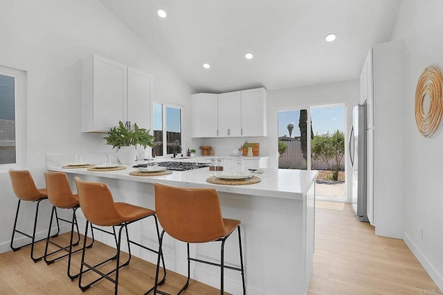 3939 Magnolia Rd, Oceanside, CA 92058 - kitchen with appliances with stainless steel finishes, a breakfast bar area, light countertops, white cabinetry, and lofted ceiling