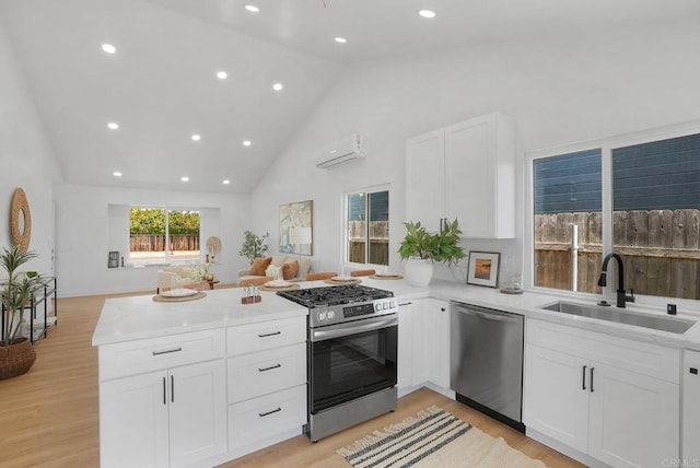 3939 Magnolia Rd, Oceanside, CA 92058 - kitchen with appliances with stainless steel finishes, a peninsula, a wall mounted air conditioner, white cabinets, and high vaulted ceiling
