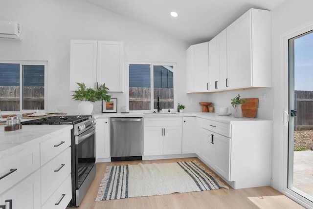 3939 Magnolia Rd, Oceanside, CA 92058 - kitchen featuring stainless steel appliances, an AC wall unit, light wood-type flooring, vaulted ceiling, and healthy amount of natural light