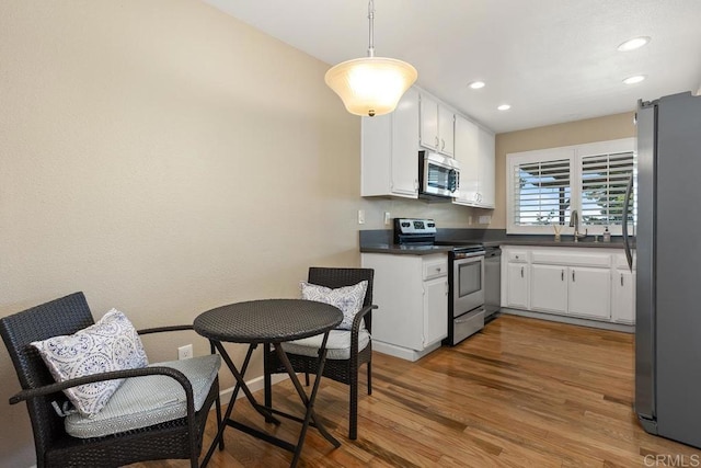 2072 Golden Circle Dr, Escondido, CA 92026 - kitchen with appliances with stainless steel finishes, dark countertops, white cabinetry, wood finished floors, and recessed lighting