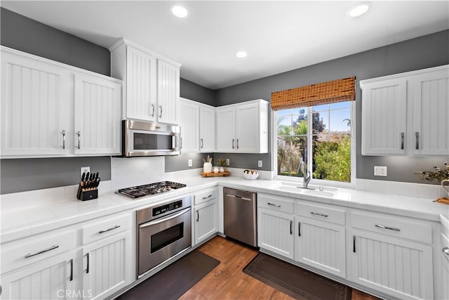 507 Corte Del Oro, San Clemente, CA 92673 - kitchen with appliances with stainless steel finishes, tile counters, white cabinetry, dark wood finished floors, and recessed lighting