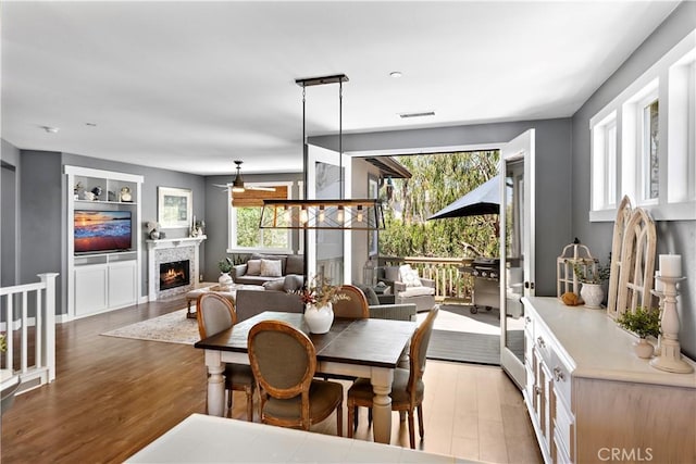 507 Corte Del Oro, San Clemente, CA 92673 - dining space featuring ceiling fan, light wood-type flooring, a lit fireplace, and built in features