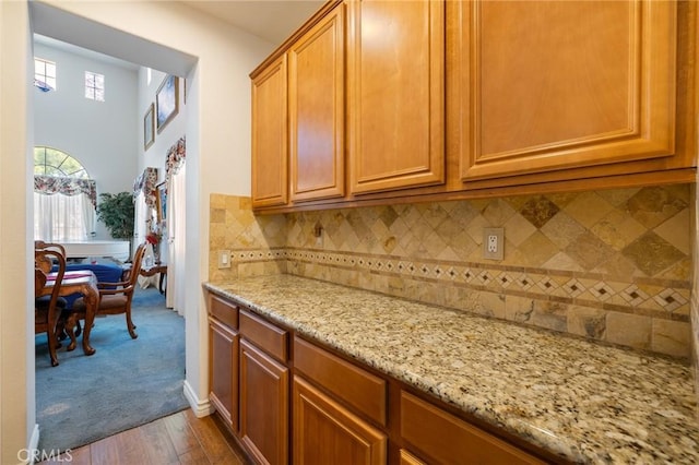 6411 Puma Pl, Rancho Cucamonga, CA 91737 - kitchen with light stone countertops, dark wood-style flooring, backsplash, and brown cabinetry
