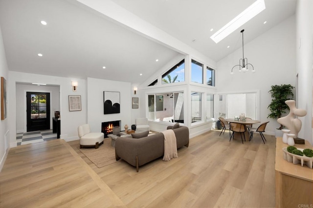 3835 Humboldt Dr, Huntington Beach, CA 92649 - living area with a warm lit fireplace, light wood-style floors, a skylight, high vaulted ceiling, and a chandelier