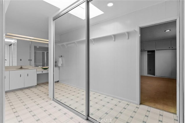 12319 Aneta St, Culver City, CA 90230 - bathroom featuring tile patterned floors, vanity, a skylight, a stall shower, and a spacious closet