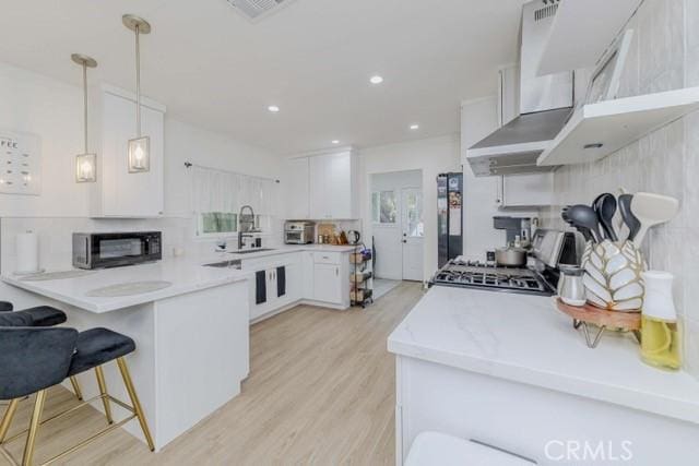 7933 Washington Ave, Whittier, CA 90602 - kitchen featuring range, wall chimney range hood, a peninsula, light countertops, and recessed lighting