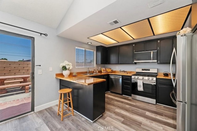 3920 Roxbury Dr, Hemet, CA 92545 - kitchen featuring appliances with stainless steel finishes, a peninsula, light wood-type flooring, light countertops, and a kitchen bar