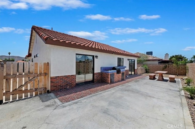 3920 Roxbury Dr, Hemet, CA 92545 - back of house with exterior kitchen, stucco siding, a patio area, and brick siding